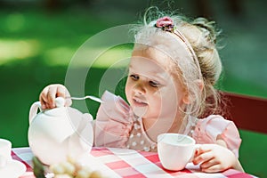 Little girl having her first tea party and learning good maners