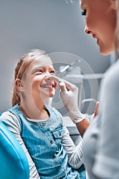 Little girl is having her teeth examined by dentist