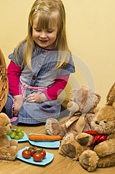 Little girl having lunch with her stuffed toys