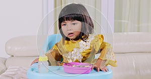 Little girl having lunch on highchair at home