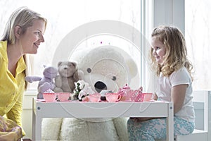 A mom and toddler daughter having a tea party.