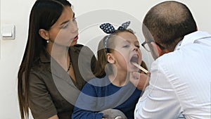 Little girl having throat examination by a male doctor photo