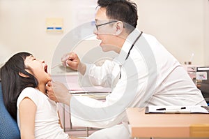 Little girl having throat examination with tongue depressor