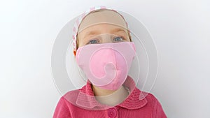 Little girl in headband and protective pink mask against coronavirus COVID-19 pandemic white background on quarantine
