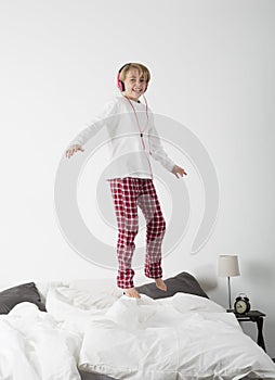 Little girl with Headphones jumping in bed