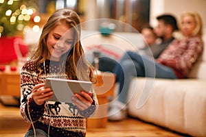 Little girl with headphones listen music on tablet and smiling