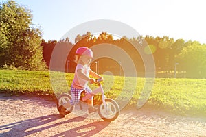 Little girl with helmet riding bike at sunset