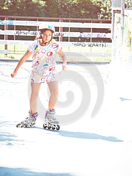 Little girl in helmet and roller skates at a park