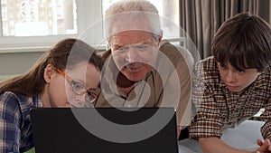 Little girl help her grandpa to type on laptop