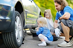 Little girl helping father to change a car wheel