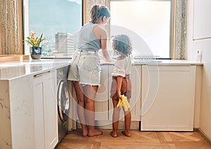 Little girl helping her mother with household chores at home. Happy mom and daughter washing dishes in the kitchen