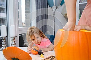 Little girl helping mommy cutting pumpkin