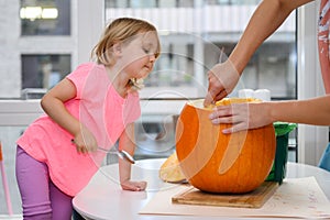 Little girl helping mommy cutting pumpkin