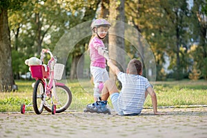 Little girl helps boy with roller skates to stand up