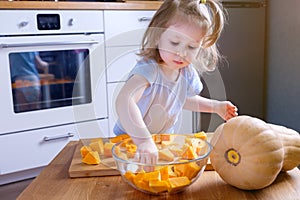Little girl helps her mother prepare a pumpkin