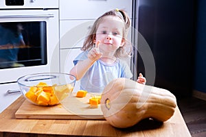 Little girl helps her mother prepare a pumpkin