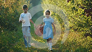 Little girl and her brother carry basket along beautiful nature. Boy is eating red apple. Slowmo. Slow motion. Copy