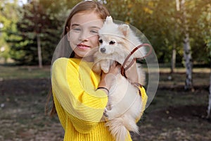 Little girl with her cute dog in park. Autumn walk