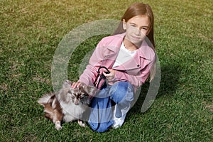 Little girl with her cute dog walking on green grass