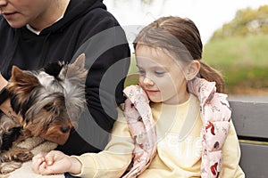 Little girl and her mom playing in the park with a Yorkshire Terrier
