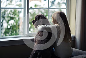 Little girl and her dog looking out the window.