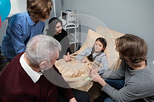 A little girl with her family in a hostipal ward after an accident, everyone in happy she is feeling better