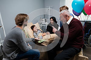 A little girl with her family in a hostipal ward after an accident, everyone in happy she is feeling better