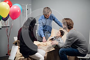 A little girl with her family in a hostipal ward after an accident, everyone in happy she is feeling better