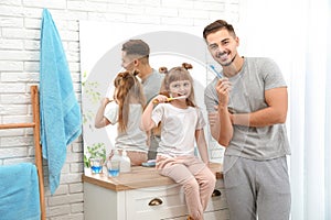 Little girl and her father brushing teeth together in bathroom at home