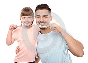 Little girl and her father brushing teeth together on white