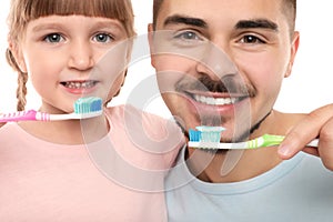 Little girl and her father brushing teeth together on white, closeup