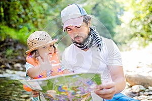 Little girl and her father exploring map in the forest or park