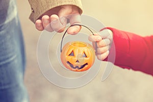 Little girl and her father, Halloween, parent and child trick or treating together. Toddler kid with jack-o-lantern.