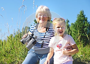 Little girl with her grandmother looking through binoculars outdoor