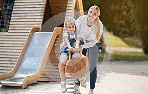 Little Girl And Her Mom Having Fun Riding On Playground