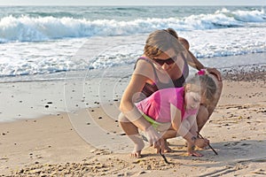 Little girl with her mom playing on the beach