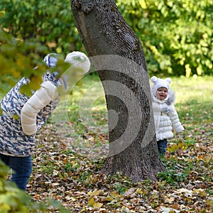 Little girl and her mom playing hide and seek in a meadow in the park