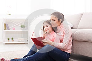 Little girl and her mom reading book at home