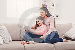 Little girl and her mom using a tablet at home
