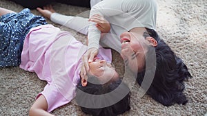 Little girl and her mother joking on carpet