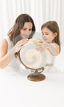 Little girl and her mother looking at a terrestrial globe