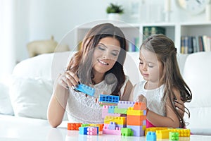 Little girl and her mother playing with colorful plastic blocks