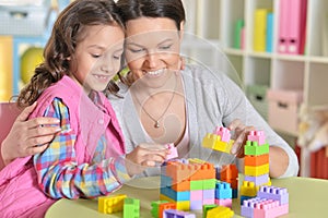 Little girl and her mother playing with colorful plastic blocks
