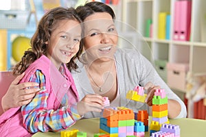 Little girl and her mother playing with colorful plastic blocks