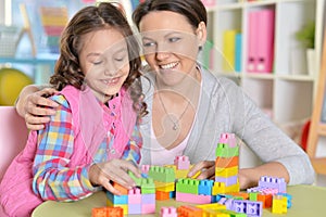 little girl and her mother playing with colorful plastic blocks