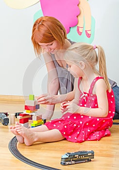 Little girl and her mother playing with railway.