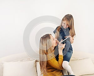 Little girl with her mother playing TV video game device on the