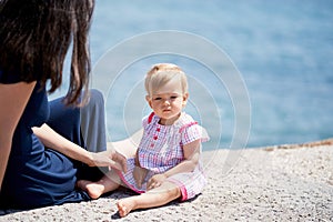 Little girl with her mother sit on the breakwater. Close-up