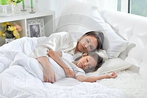 Little girl and her mother sleeping in her bed