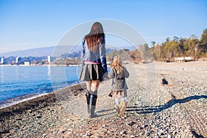 Little girl and her mother walking on the beach in